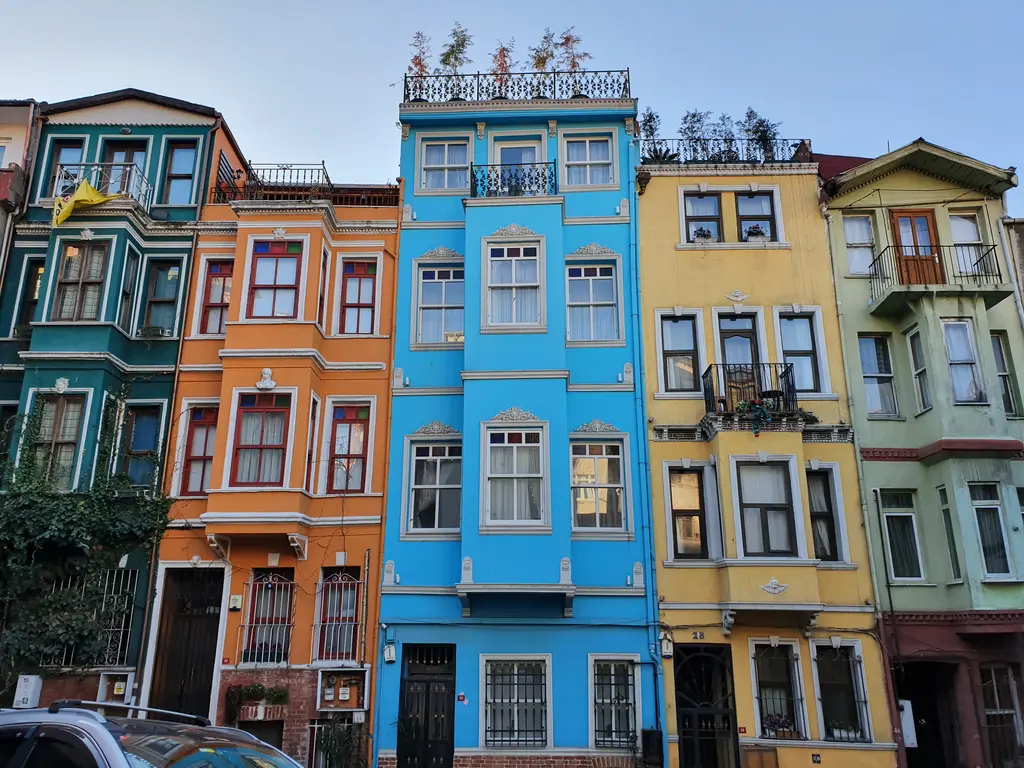 Balat'ta yan yana dört renkli ev; yeşil, turuncu, mavi ve sarı cepheler, cumbalar ve çatılarda bitkiler.