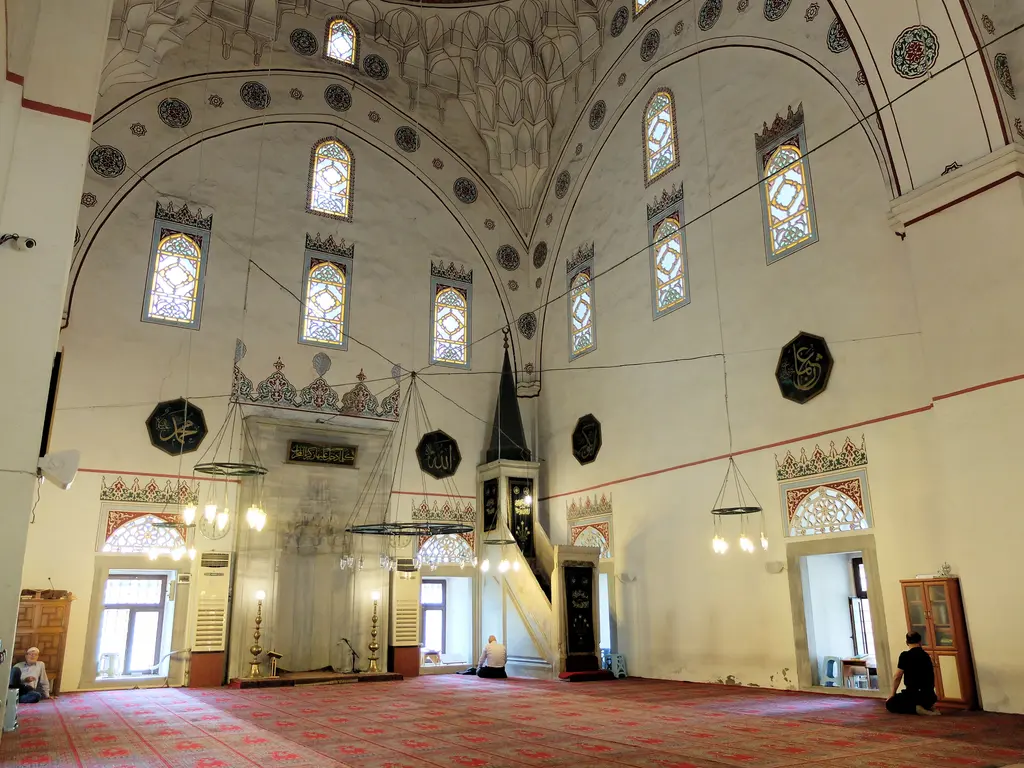 Murat Paşa Camii'nin harimi; kırmızı halı, mermer mihrap ve minber, kalem işli kemerler, iki sıra pencere ve asılı avize halkası.