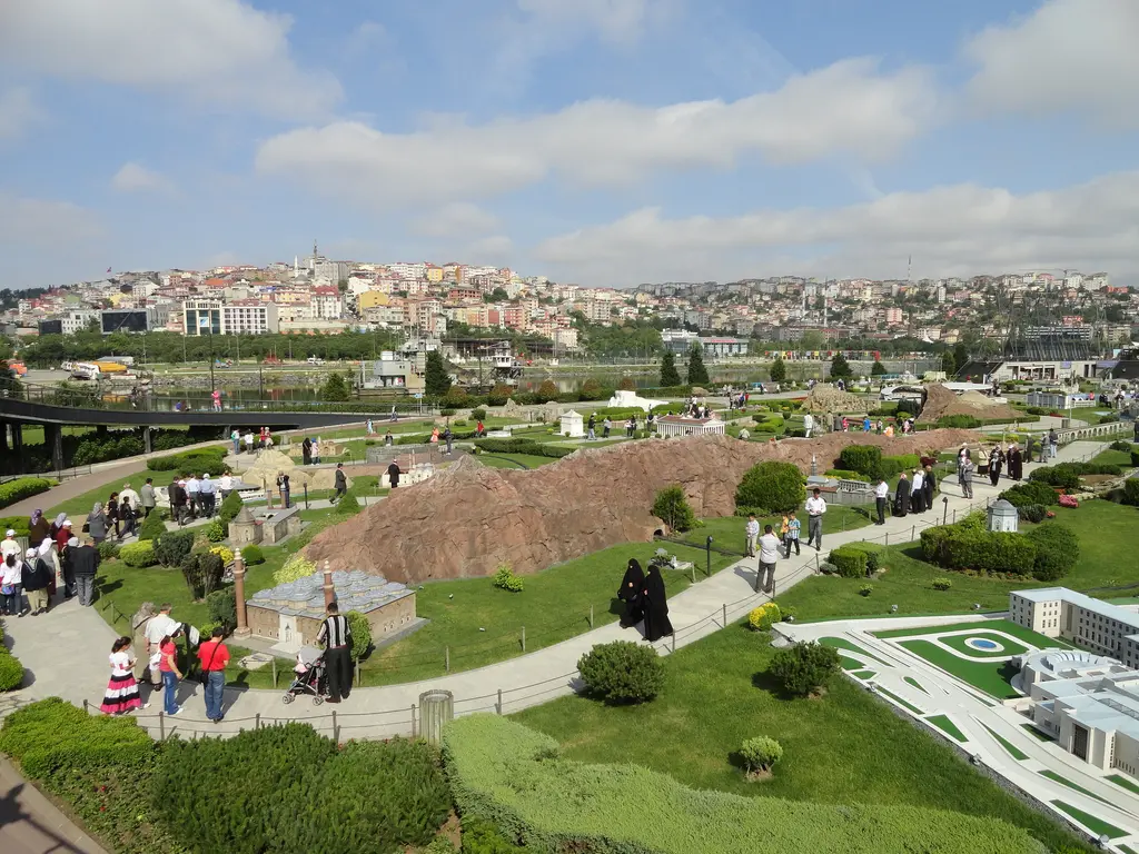 Miniatürk'te maket alanı; ortada kızıl kayalık bir tepe maketi, çevresinde yürüyüş yolları ve ziyaretçiler, arkada Haliç ve kıyıdaki evler.