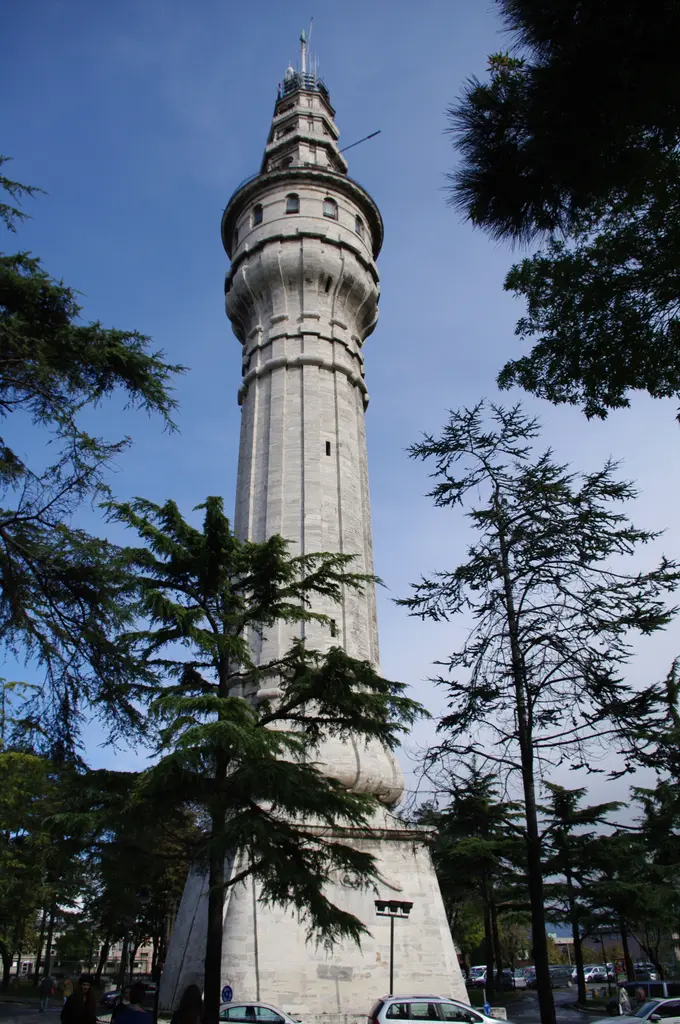 Beyazıt Kulesi'nin gövdesi; uzun ağaçların arasından yükselen taş kütle, kaide bölümü ve üst katların oluşturduğu kademeli siluet.