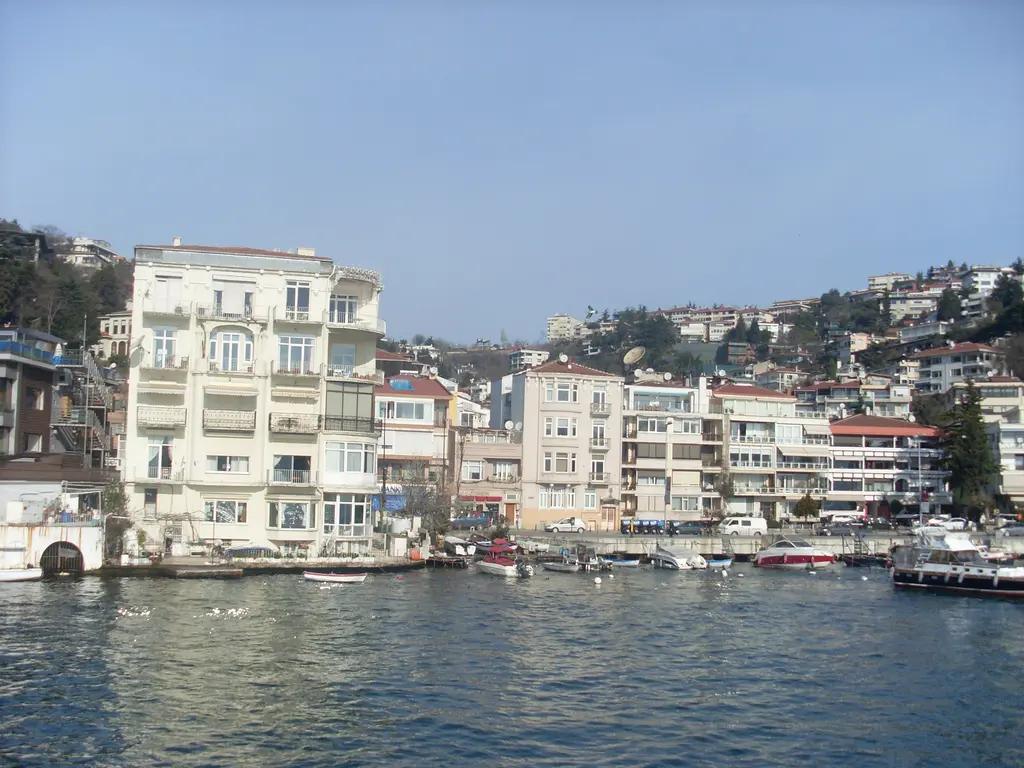 Bebek kıyısında yan yana dizilen binalar; çok katlı beyaz apartman, kıyıda yalılar ve demirli tekneler.