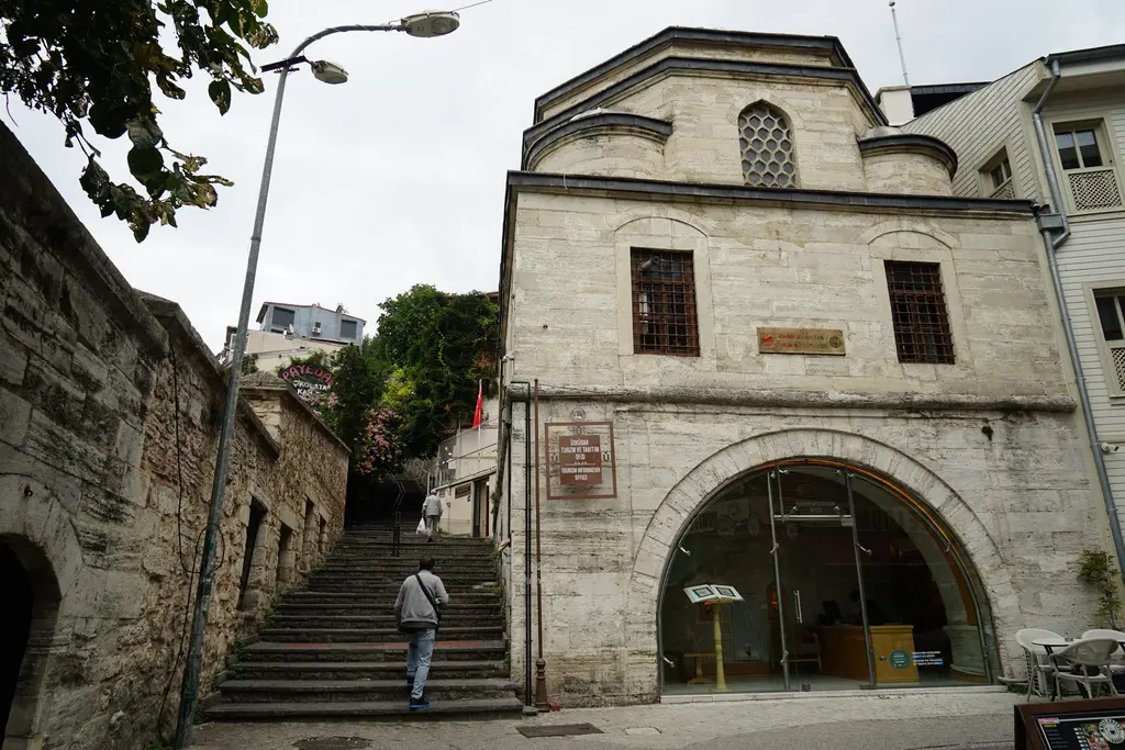 Mihrimah Sultan Sıbyan Mektebi; kesme taş yapı, kemerli giriş, yanından yükselen merdivenli sokak.