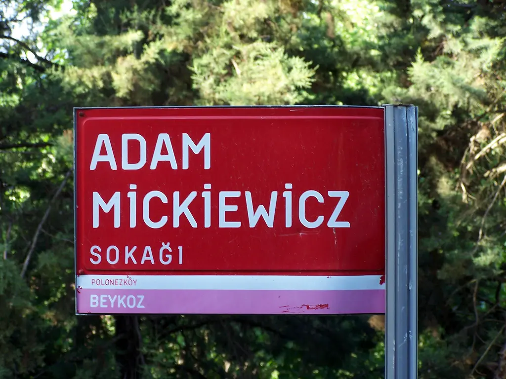 Polonezköy'de ağaçların önünde kırmızı sokak tabelası; üstünde "Adam Mickiewicz Sokağı" yazısı ve altında Polonezköy, Beykoz.