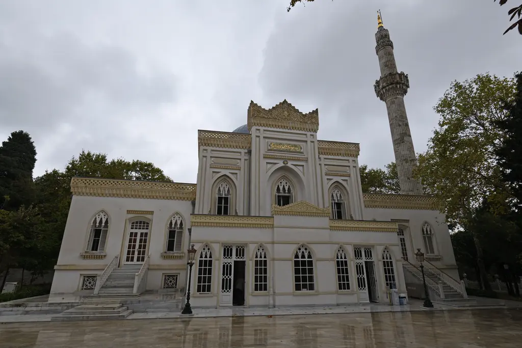 Yıldız Hamidiye Camii'nin kuzeybatı cephesi; taçkapı biçimli yüksek giriş, iki yanda mermer merdivenler, ıslak taş avlu ve minare.