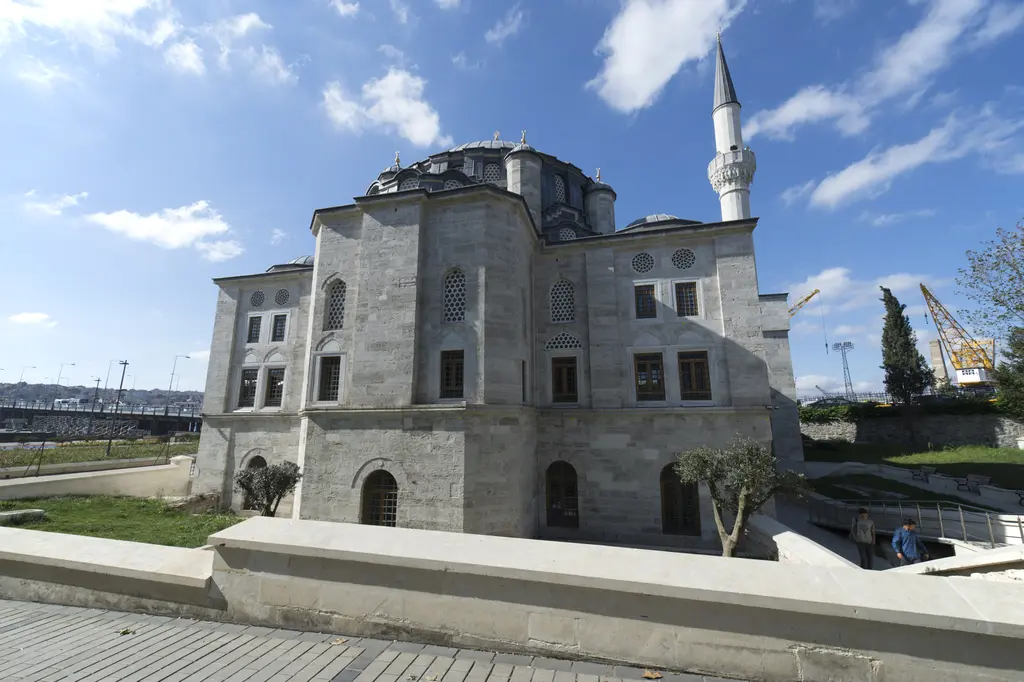 Azapkapı Sokullu Mehmed Paşa Camii'nin kıyı tarafı; taş cephe, kubbe ve minare, önde çimen, zeytin ağacı ve alçak taş duvarlar.