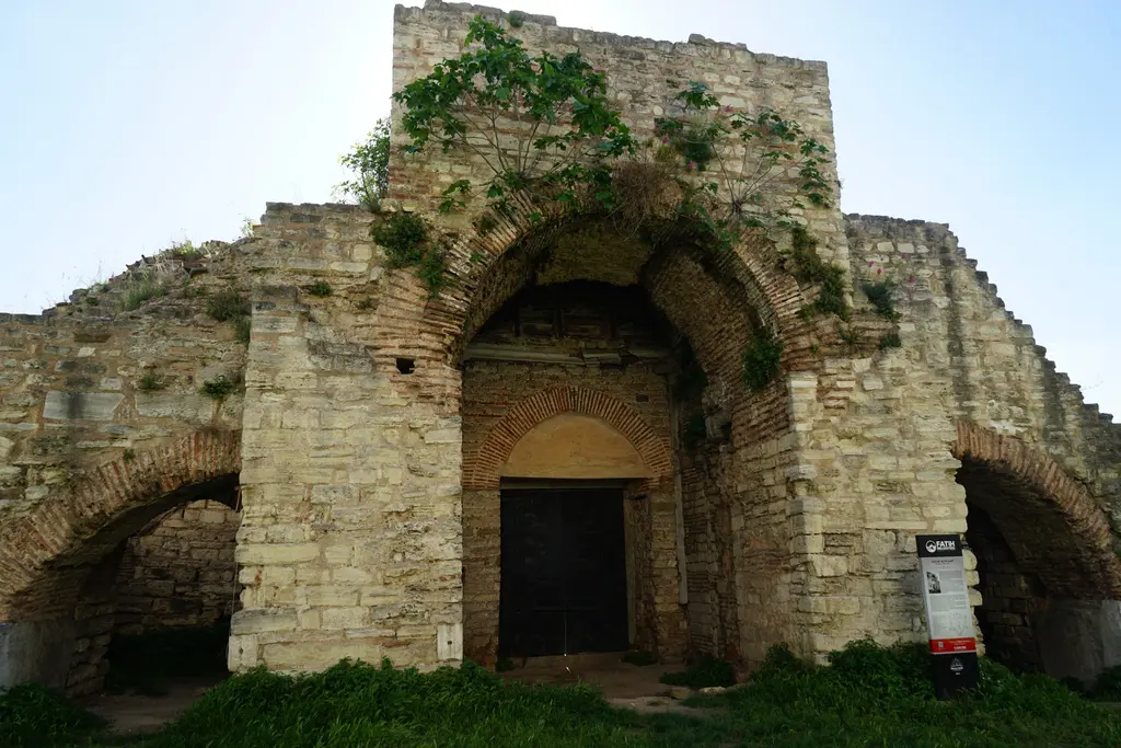 Yedikule'de Küçük Altın Kapı; sarmaşıkla kaplı büyük kemerli kapı kütlesi, ortada ahşap çift kanatlı kapı, üstünde tuğla boşaltma kemeri ve iki yanda küçük kemerli geçitler.