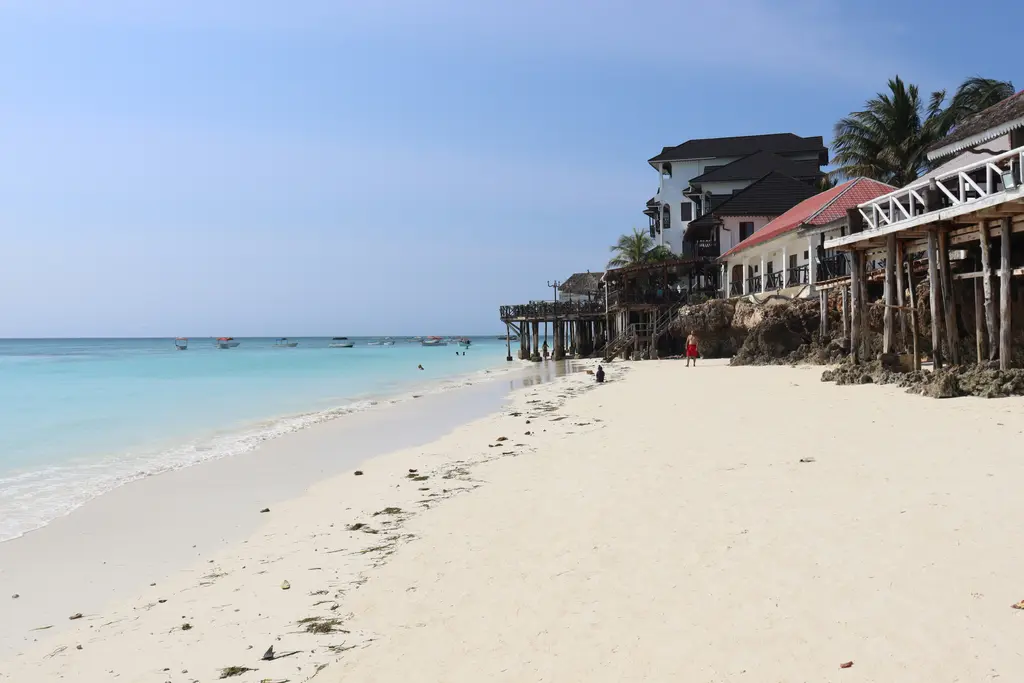 Zanzibar'ın kuzeyinde Nungwi plajı; beyaz kum, kıyıya çekilmiş dhow tekneleri ve açık turkuaz su.