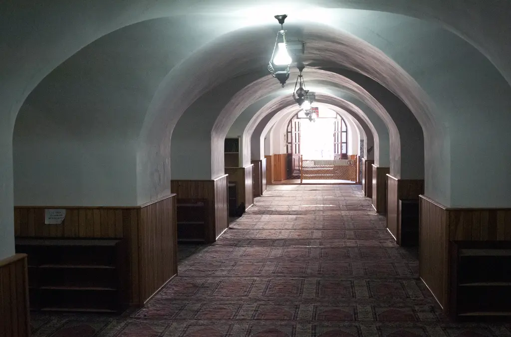 Yeraltı Camii'nin içi; uzun tonozlu koridor, halı kaplı zemin, ahşap lambri ve tavandan sarkan avize.