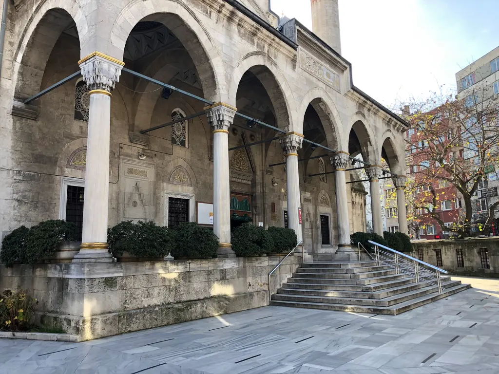 Şişli Camii'nin son cemaat yeri; beyaz mermer sütunlu kemerli revak, avludan çıkan geniş merdiven ve önde mermer döşeli avlu.